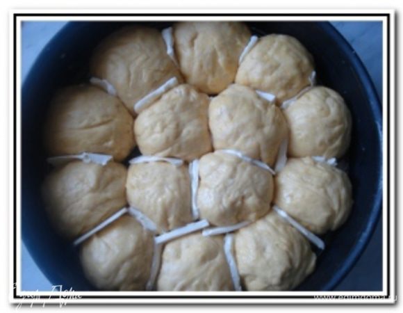 Разделить тесто на кусочки и скатать из них шарики. Выложить шарики в смазанную маслом форму для выпечки. Между шариками хорошо бы проложить кусочки сливочного масла, легче будут отделяться булочки друг от друга. Накруть пампушки полотенцем и поставить в теплое место на 20-25 минут.