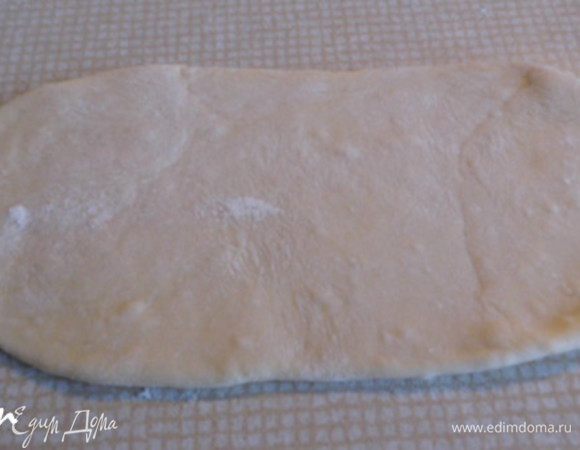 Готовое тесто разделить на 2 равные половинки. Одну половинку теста поместить в целлофановом мешочке  и убрать в холодильник (на потом). А из другой раскатать  "колбаску" и разделить её на 8 равных частей, из которых скатать шарики, обпылить мукой и сформировать лепёшечку  (приплюснуть посередине).
Из лепёшки раскатать пластик-"язычок" размером 20х10 см.