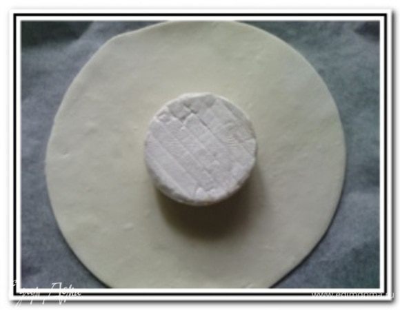 Тесто разделить на две части. Раскатать одну часть теста и вырезать тарелкой круг. Перенести этот круг на выстланный пергаментом противень. В центр круга положить сыр бри.