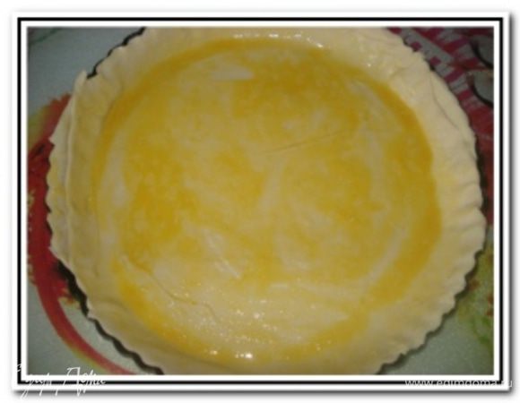 Форму для выпечки смазать растительным маслом. Тесто раскатать и выложить им форму для выпечки. Сверху пройти скалкой для удаления лишних остатков теста. Основание смазать взбитым желтком с оливковым маслом.