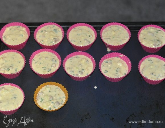 Форму для кексов смазать маслом, заполнить тестом на 2/3 и посыпать сверху потертым сыром.Поставить в предварительно разогретую духовку и выпекать 20-25 мин.
