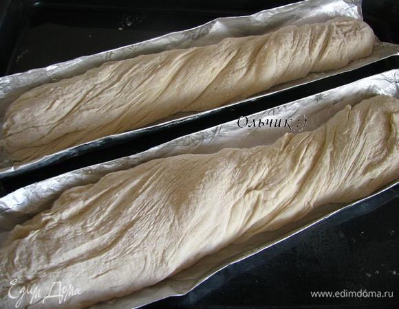 Присыпаем тесто мукой со всех сторон, аккуратно разделяем его на 2 части. Легкими движениями формируем багеты, слегка перекручиваем тесто одновременно вытягивая его по длинне формы. Укладываем в формы.