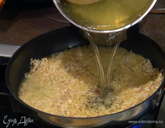 Всыпать в сковороду рис и прогревать в течение минуты, чтобы он пропитался маслом, затем добавить лавровый лист, куркуму, гвоздику, залить горячим бульоном, довести до кипения и варить на маленьком огне минут 10–15 — бульон должен увариться.