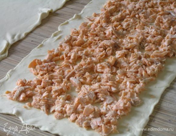 Тесто немного раскатать, разрезать на 2 части. На одну из них выложить рыбу,