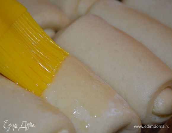 Через полчаса рулетики увеличатся в размере опять. Смазать их оставшимся сливочным маслом и отправить в духовку на 25 минут при 180°C.