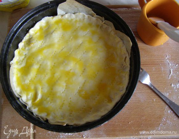 Меньшую часть теста раскатать по диаметру формы, накрыть начинку, защипнуть края, смазать желтком и наколоть вилкой