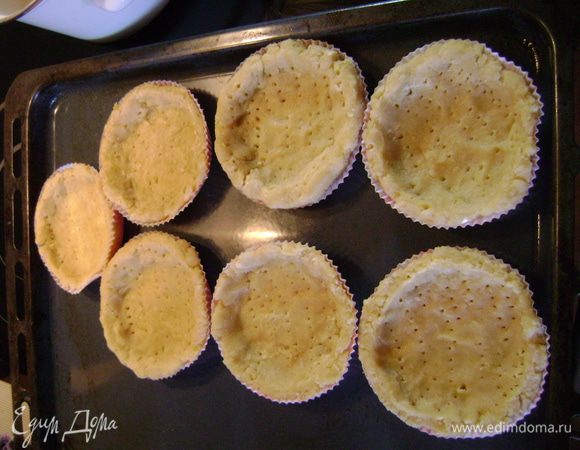 На посыпанной мукой рабочей поверхности раскатать тесто. Смазать маслом формочки для тартинок или для пирога (если формочки бумажный, смазывать не нужно), выложить в них тесто и много раз наколоть вилкой.