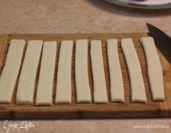 Разморозьте тесто. Чтобы оно не подсохло сверху - посыпьте слегка мукой и накройте чистым пакетом или пленкой. Нарежьте тесто на 9-10 полосок - около 2-х сантиметров шириной.