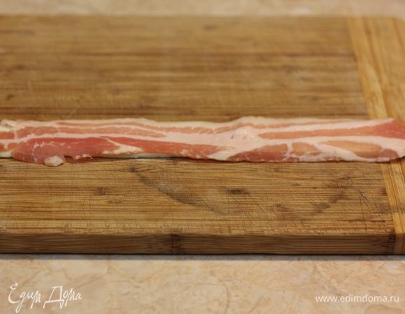 Аккуратно раскатайте полоску теста длиной немного больше, чем ломтик бекона - на пару сантиметров длиннее (около 30 сантиметров). Положите сверху бекон. В начале я клал просто сверху бекон, а потом стал складывать его три раза вдоль. Получалось что-то вроде трубочки.