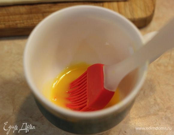 Отделите желток от белка. Налейте в желток одну чайную ложку холодной воды и хорошо размешайте. Так будет намного легче намазывать желток на выпечку.