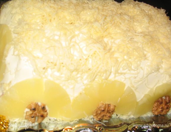 Поскольку мой салат называется закусочным тортом, придется его украсить, но только перед самой подачей! Достать из холодильника пласт 1 (сметанно-майонезный) и, аккуратно отделив его от формы, накрыть торт сверху...снова посыпать сыром, а по бокам разложить полукольца ананаса и грецкие орехи. Если кольца очень толстые можно разрезать их вдоль, чтобы они стали потоньше и изящнее