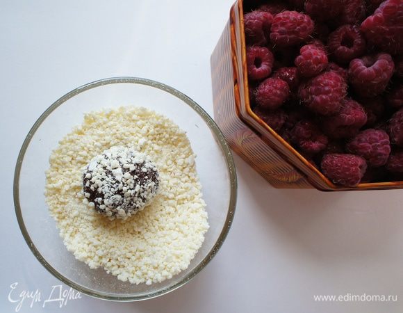 Достать из холодильника шоколадную смесь. Сформировать конфетку, в серединку которой положить малину.
Обвалять в крошке белого шоколада.