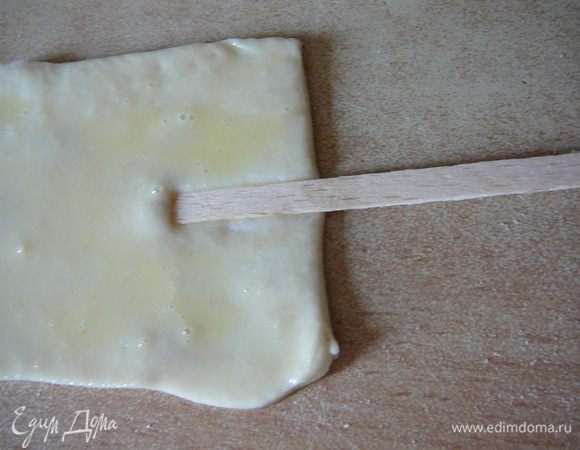 Берем прямоугольник из теста, слегка растягиваем в стороны. Смазываем взбитым яйцом,особенно уделяем внимание краям( я поспешила и в итоге края слегка расклеились). Укладываем аккуратно палочку, примерно в центр прямоугольника,слегка вдавливаем ее в тесто.