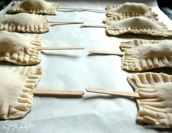 Края прижать пальцами и защипать с помощью вилки. Выложить на противень, смазать взбитым яйцом и присыпать сахаром.