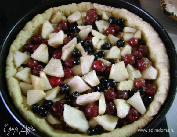 Вытащить корж из духовки, убрать горох или фасоль, вытащить пергаментную бумагу. Посыпать корж толченым печеньем или сухарями и выложить ягоды и яблоки. Отправить в духовку на 10 минут.  