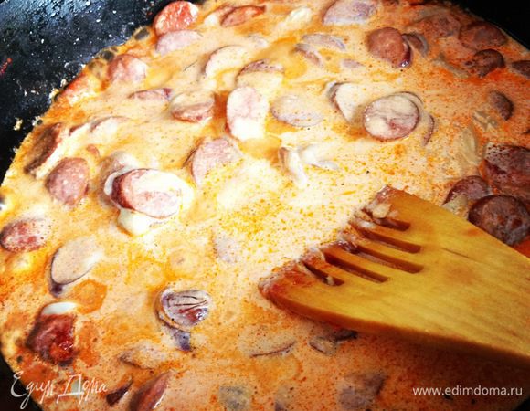 Когда калбаски немного обжарились добавляем сок от томатов в собственном соку, мешаем, через минуту добавляем сливки, основную часть сыра, мешаем. (По желанию можно добавить ложку томатной пасты и сметаны).