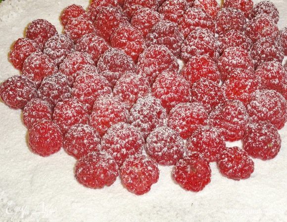 Когда ганаш застынет, украсьте торт ягодами малины и посыпьте сахарной пудрой (по желанию)