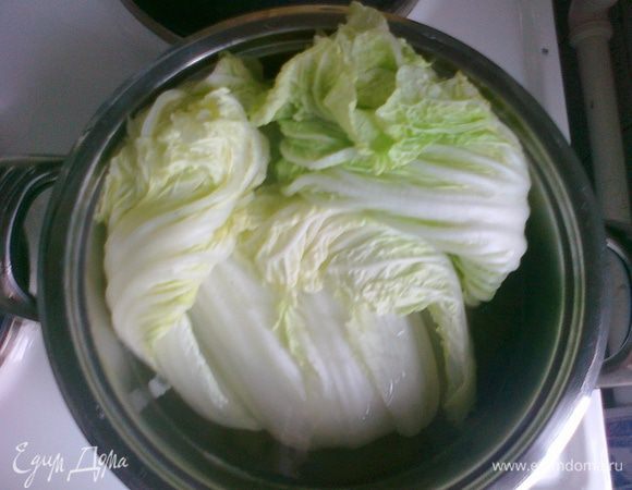 3. Пекинскую капусту разбираем на листы. Складываем в кастрюлю толстыми основаниями листа вниз. Доводим до кипения, бросаем щепотку соли, держим капусту на огне, пока листья не размягчатся, чтобы стать податливыми (сильно разваривать не надо). Если капуста изначально совсем нежная, достаточно просто обдать кипятком.