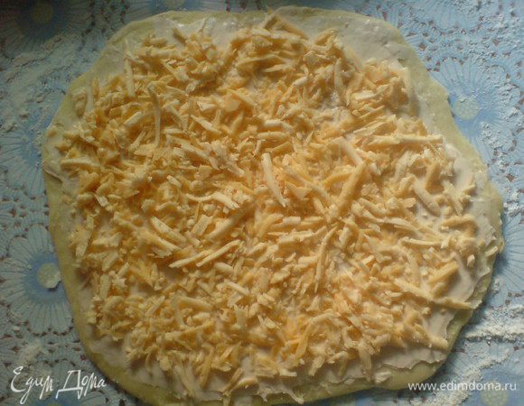 Тесто раскатать в пласт толщиной в несколько мм.Намазать сливочным или плавленным сыром. Сверху присыпать тертым сыром (немного сыра оставить, чтобы присыпать потом наши булочки). 