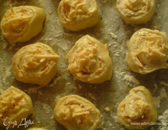 Свернуть тесто в плотный рулет.Нарезать ломтиками толщиной 1 см.Выложить на противень,выстеленный бумагой для выпечки (я еще присыпала мукой). Смазать булочки яйцом,положить по несколько кусочков чеснока,присыпать оставшимся сыром.
Выпекать в духовке при средней температуре 25 минут.