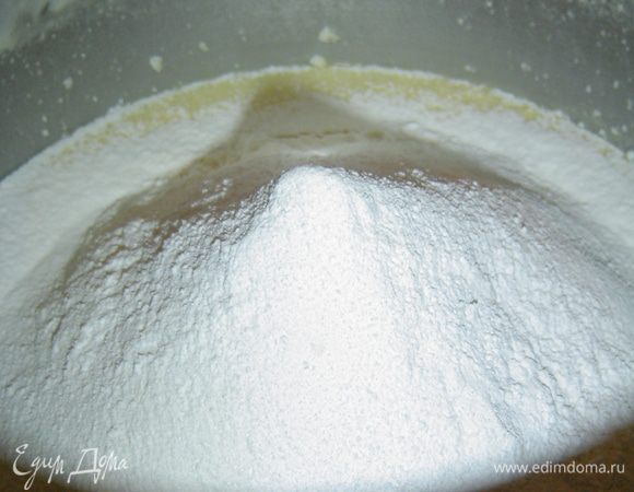 Следующим этапом вливаем молоко, добавляем ванильный сахар, просеянную муку с разрыхлителем и аккуратно перемешиваем ложкой.
