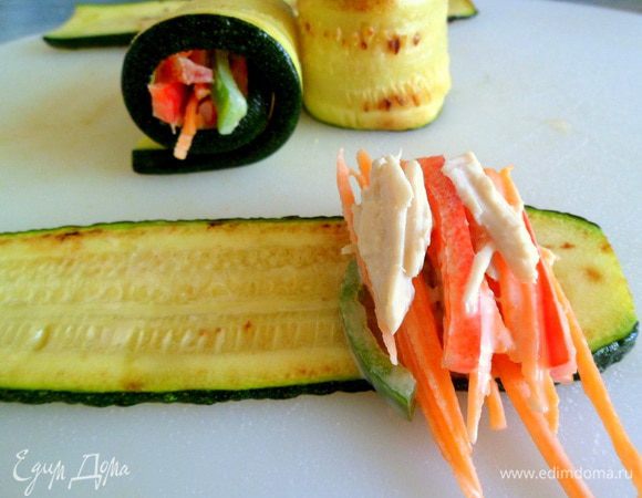 На ломтик цукини выложить немного начинки, стараясь нарезанное все соломкой вертикально положить. Затем свернуть в рулет, если нужно то все закрепить зубочисткой или завязать перышком лука