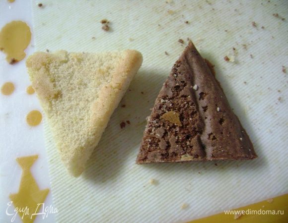 Снять пергаментную бумагу с бисквитов и нарезать прямоугольные бисквиты треугольниками, ориентируясь по форме, со стороной примерно 3 см. 