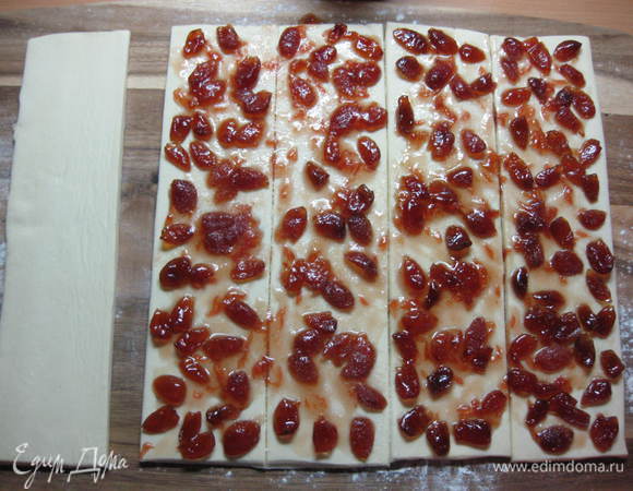 Одну полосу отложить в сторону, а остальные (не разделяя их) намазать джемом тонким слоем и слегка присыпать сахаром.