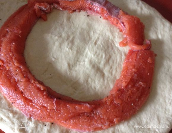 Раскатать тесто в круг толщиной 0,6 см. Отступив от края 3,5 см, по кругу выложить полоски или кусочки рыбы, нарезанные в 2,5 см толщиной, накрыть тестом с краев и хорошо залепить шов.