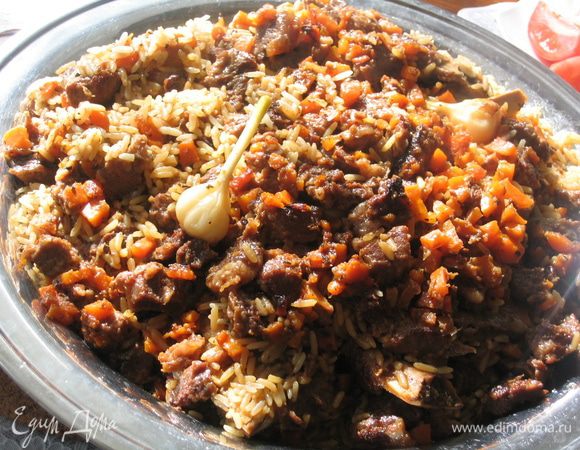 Подавать плов следует на общем блюде или подносе, выложив его аккуратно из казана так, чтобы все мясо оказалось сверху, разложить пропаренный чеснок, свежую зелень и помидоры. Безумно вкусный плов, поверьте. Приятного аппетита