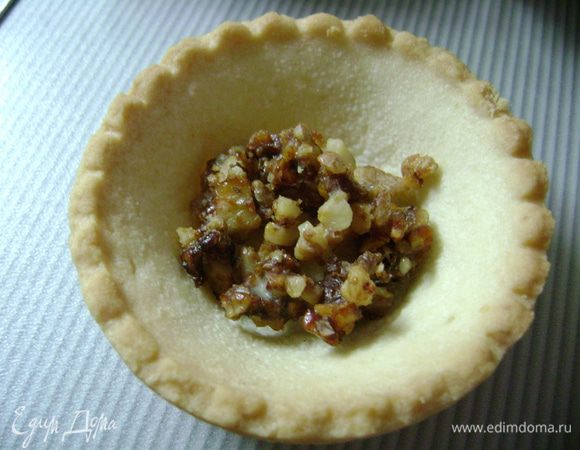 На дно тартинки кладем чайную ложку орехового кроканта (у меня в холодильнике всегда есть он). Для кроканта 50 г сахара растопить в сковороде, добавить 40 г сливочного масла, затем всыпать 100 г измельченных до кусочков орехов. Пару минут подержать, остудить. 