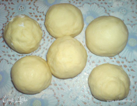 Сливы и абрикосы вымыть и высушить. Удалить из них косточки. Это нужно делать аккуратно, поскольку фрукты должны остаться целыми. В каждую сливу и абрикос положить по одному куску рафинада или по 1 ч.л. сахара.
Присыпать стол мукой. Сделать из теста валик диаметром 5 см и нарезать его на 12 кусков. Каждый кусочек раскатать, положить по сливе/абрикосу и завернуть тестом, плотно защипывая края. Получаются довольно большие шарики.
