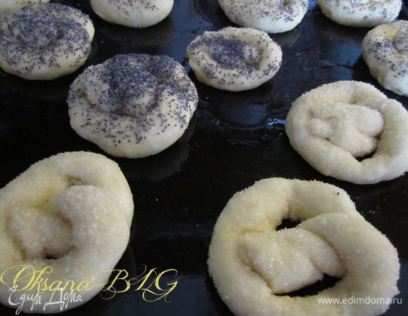 Смазать оставшимся белками и мокнуть в сахар или мак, можно сделать смесь мака и сахара или сделать соленые крендельки, посыпав их крупной морской солью. Выложить на противень смазанный растительным маслом или застеленный пергаментной бумагой.