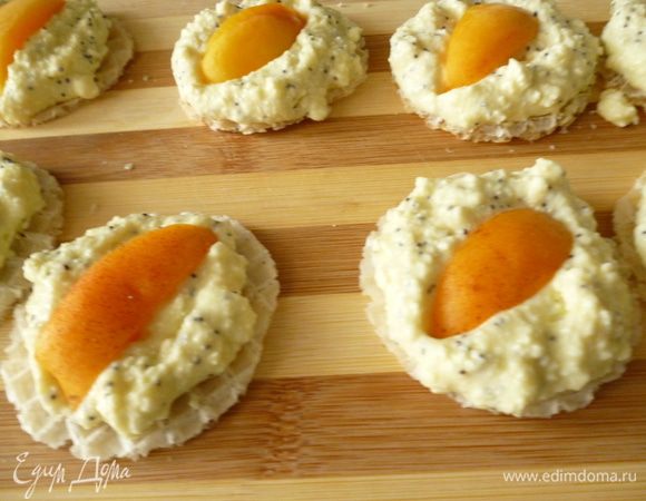 Выкладываем на каждый столовую ложку творожной массы. На нее выкладываем по дольке абрикоса.