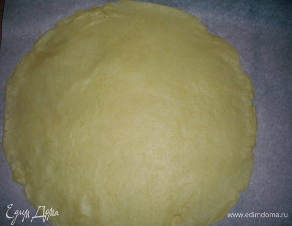 Раскатываем песочный корж на пергаменте. Его диаметр должен соответствовать диаметру выпеченного бисквита.