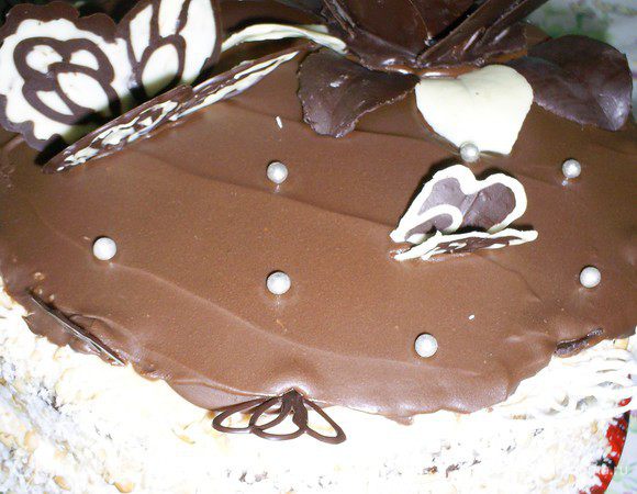 Для глазури плитку шоколада растопить с малом. Дать немного остыть и нанести на верх торта прямо на слой масляного крема.
Бока торта я обсыпала кокосовой стружкой, а верх украсила шоколадными бабочками, листиками и цветком.
Можно показывать торт публике и требовать восторженных оваций! Приятного аппетита.