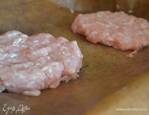 Фарш посолите и поперчите. Разделите на 2 части и сформируйте лепешки. Выложите на противень, смазанный маслом.