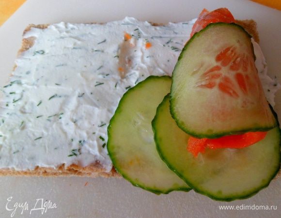 На каждый хлебец положить тонкий ломтик семги, свежий огурец и завернуть рулетиком. Скрепить зубочистками.