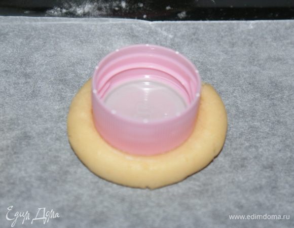 Противень застилаем пергаментом и выкладывает туда шарики. 
Пробкой от пластиковой бутылки придавливаем шарик, чтобы получилось углубление.