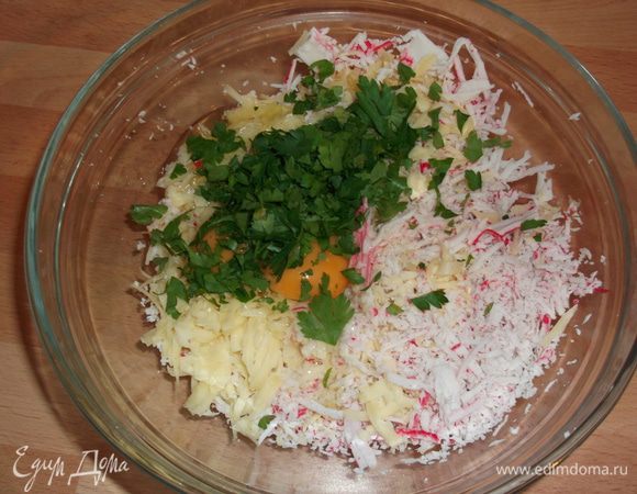 замороженные крабовые палочки натираем на мелкой терке,сыр натираем на крупной тёрке,чеснок выдавливаем,добавляем 2 яйца,мелко порезанную зелень и всё перемешиваем

