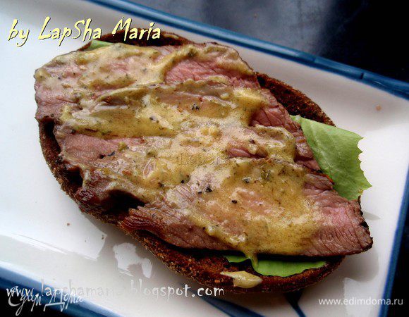 На соус выкладываем любую свежую травку. У меня на тот момент был только латук. Сверху пристраиваем ломтики говядины и смазываем их оставшимся соусом.