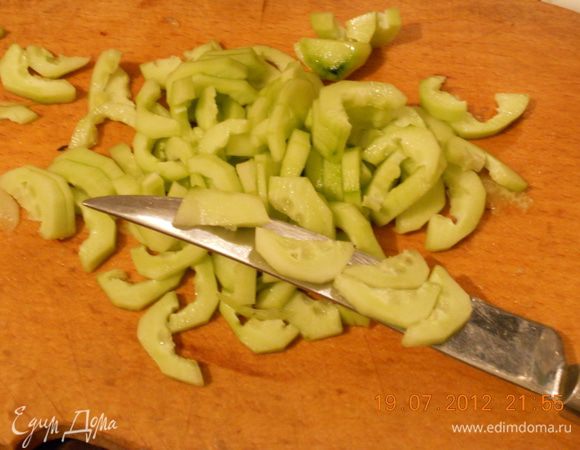 Очичтите огурцы, разрежьте их пополам и ложечкой выньте семена, а мякоть  нарежьте тонкими ломтиками. Лук и чеснок мелко порежьте.
