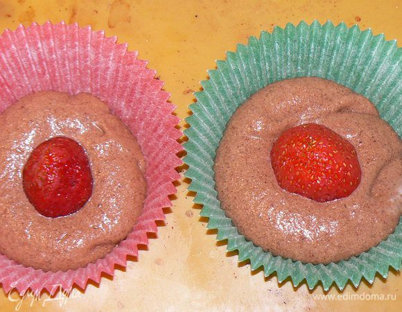 Выложить немного теста в формочки.Затем клубничку и снова тесто.