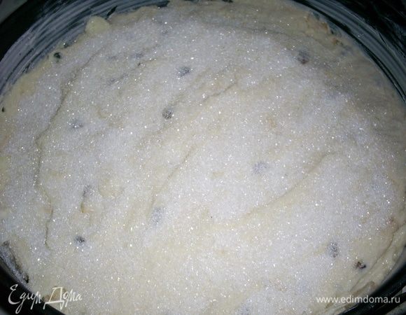 Добавить порезанные кубиками яблоки и промытый изюм. Перемешать ложкой. Выложить тесто в форму диаметром 26см, дно которой выложенное бумагой и промаслено маслом. Посыпать сверху сахаром. Выпекать в разогретой до 200 духовке около часа. Пирог сверху должен покрыться твердой корочкой, но из-за яблок средина остается слегка влажной.