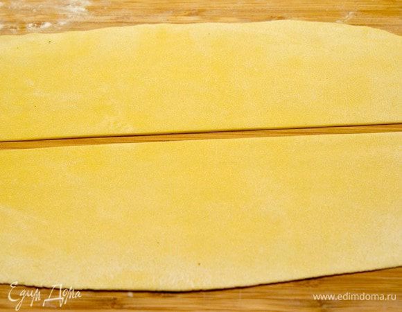 Достаньте тесто из холодильника, разделите пополам и тонко (действительно тонко) раскатайте на чуть присыпанной мукой поверхности. 