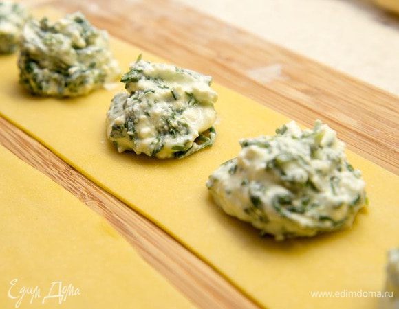 Уложите на тесто через равные промежутки по одной столовой ложке начинки. Свободные края смажьте с помощью кисточки водой и накройте сверху вторым листом. 