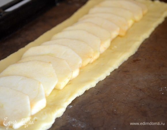 По центру теста выкладываем ломтики яблок внахлест..по всей длине пласта, оставить лишь края 2-3 см. 