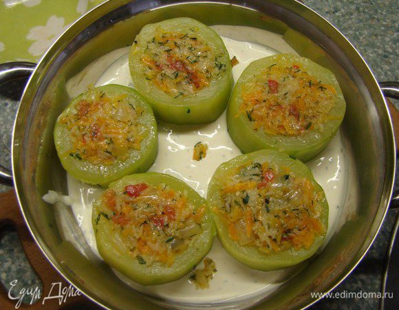 Влить в сотейник или глубокую сковороду сметанный соус. Выложить цукини. Наполнить фаршем и томить на среднем огне 25-30 минут. 