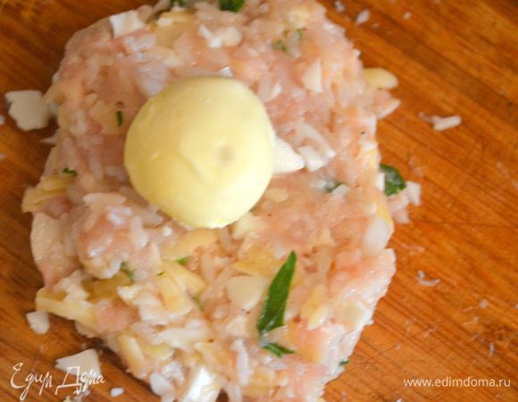 Из готового фарша должно получиться 4 большие тефтели. Делим фарш на 4 части, а каждую часть на попалам и формируем лепешку, на которую кладем желток. 