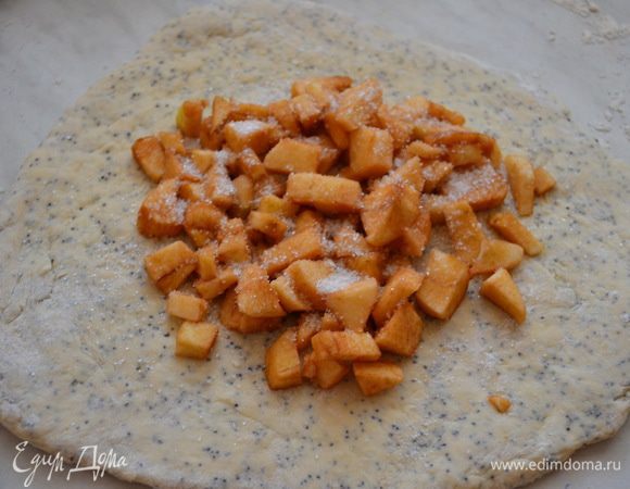 Раскатать, выложить очищенные и порезанные на кубики яблоки, посыпать сахаром.